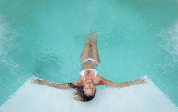 Beautiful woman relaxing at the swimming pool Beautiful Asian woman relaxing at the swimming pool at the spa hydrotherapy stock pictures, royalty-free photos & images