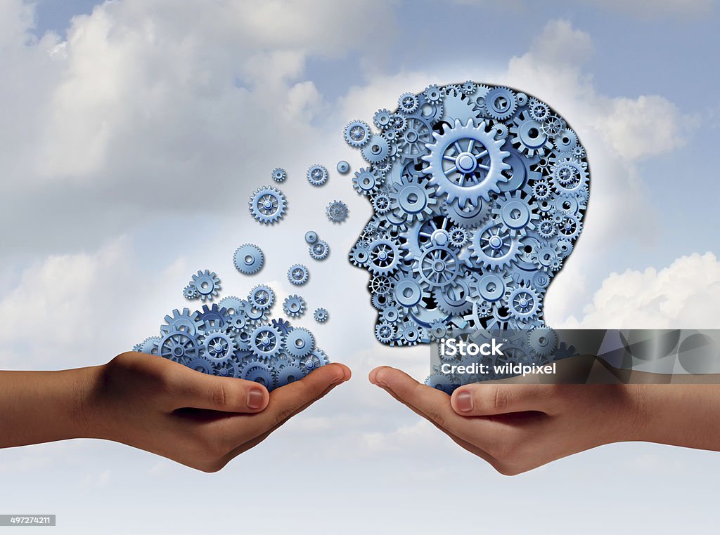 Training And Development Training and development business education concept with a hand holding a group of gears transfering the wheels of knowledge to a human head made of cogs as a symbol of acquiring the tools for career learning. Gear - Mechanism Stock Photo