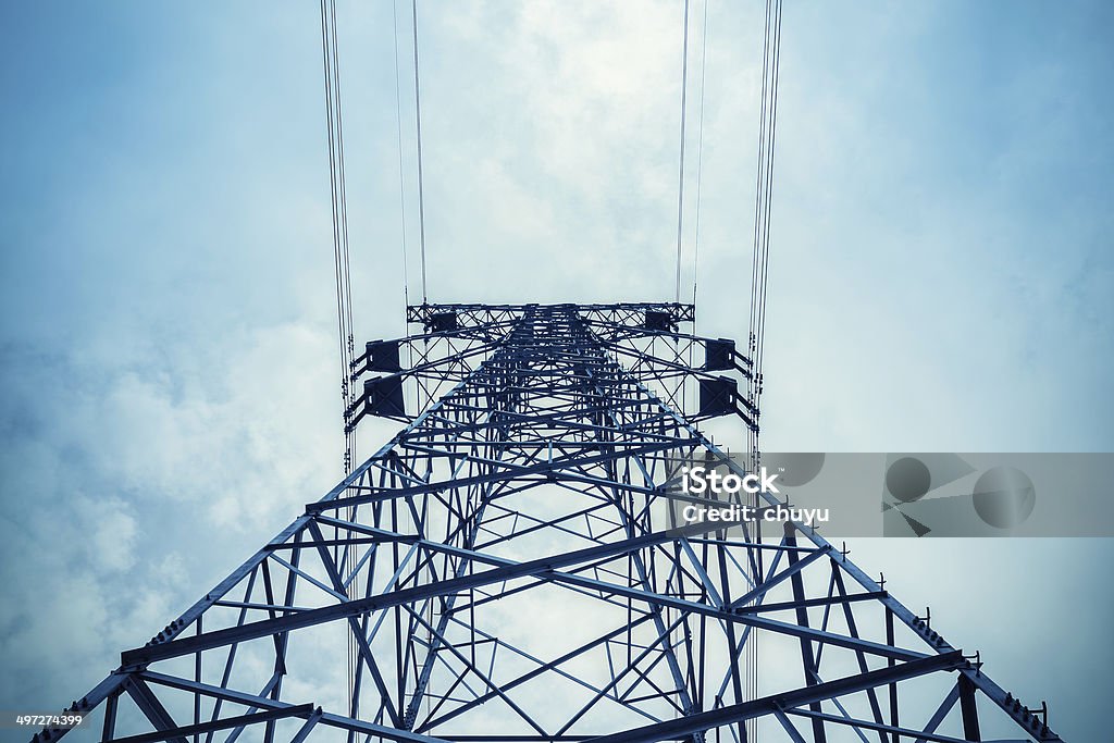 upward view of the power transmission tower upward view of the power transmission tower in a cloudy sky Blue Stock Photo