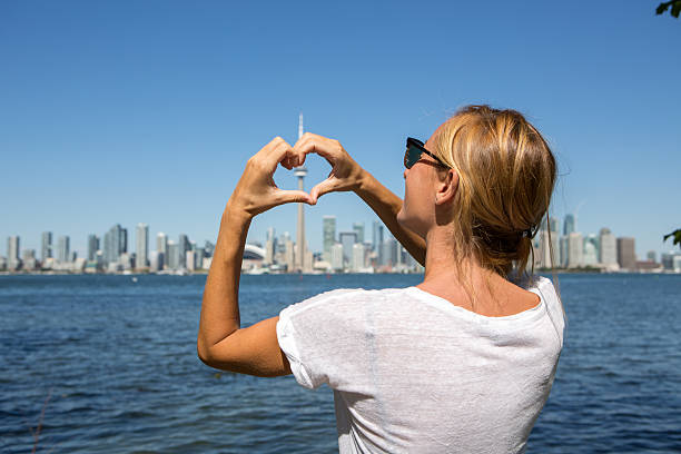 istock Young woman making heart shape frame to Toronto city 497278502