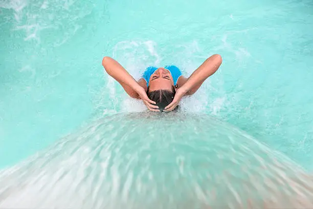 Beautiful woman relaxing at the spa in the swimming pool under a stream of water