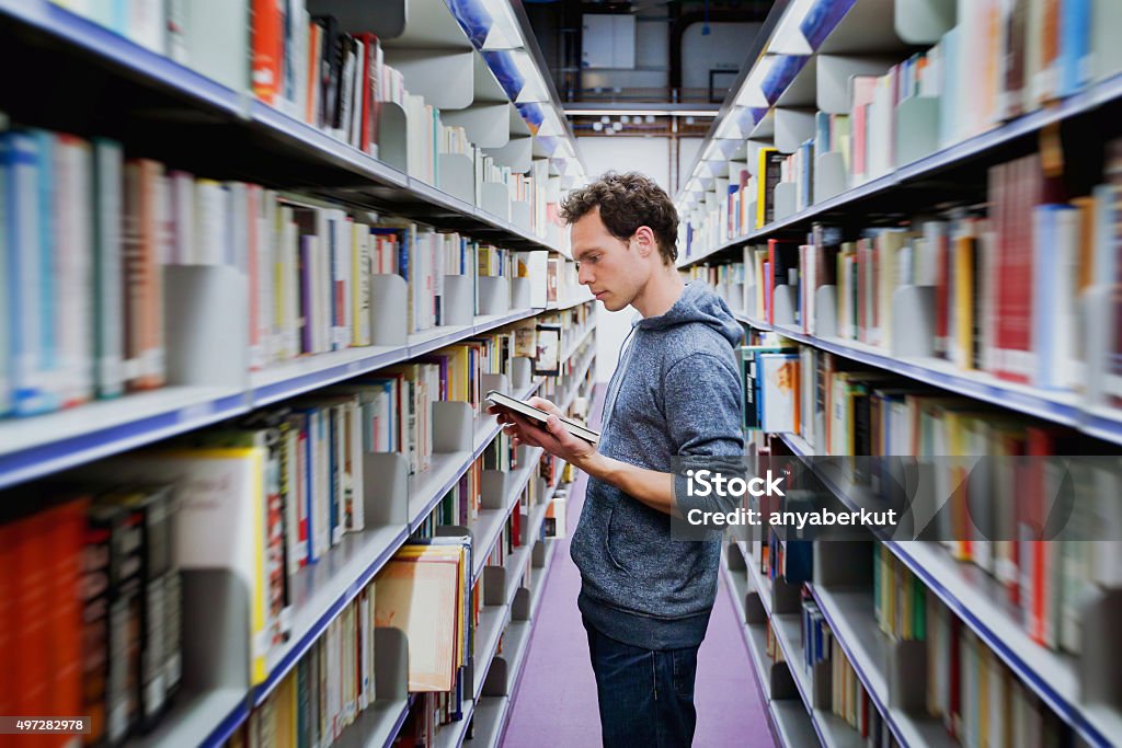 Schüler lesen Buchen Sie zwischen den Regalen in der Bibliothek - Lizenzfrei Bibliothek Stock-Foto