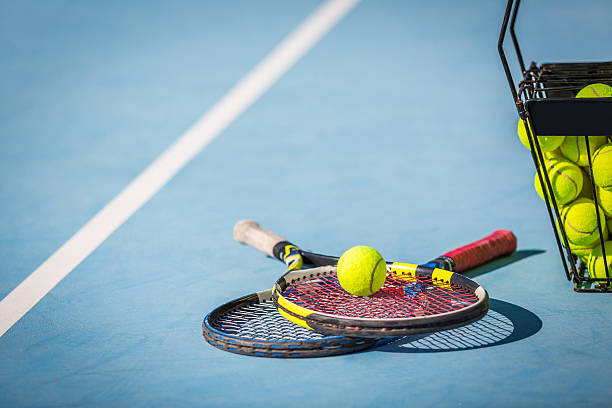 Tennis Practice tennis balls in a basket with a racket. tennis ball container stock pictures, royalty-free photos & images