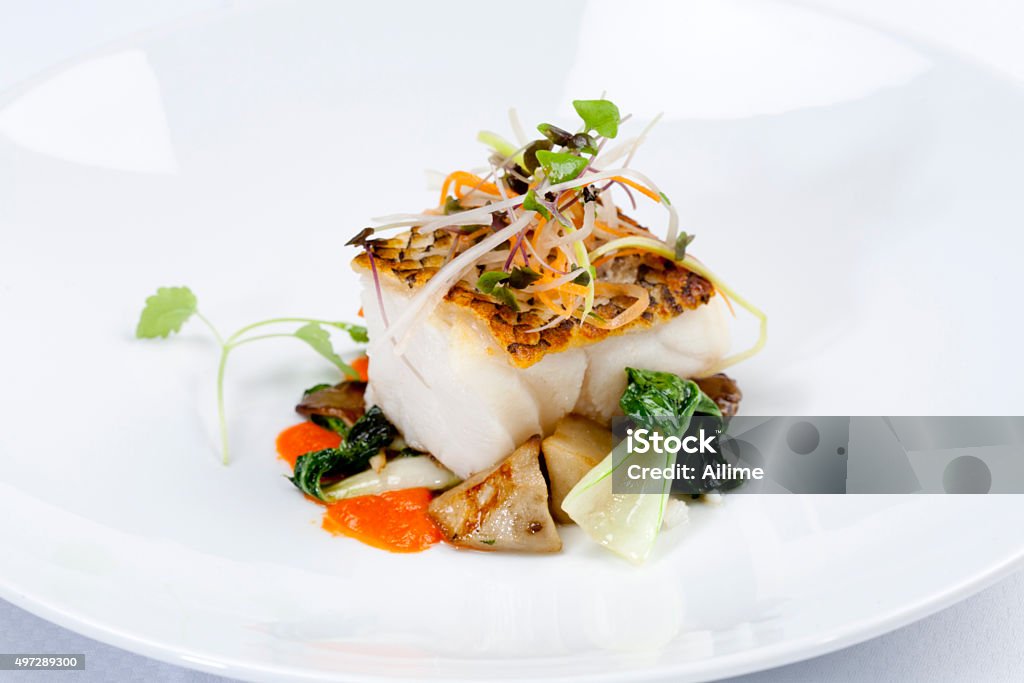 Dinner Grilled Sea Bass dinner, with vegetables on white plate. Gourmet Stock Photo