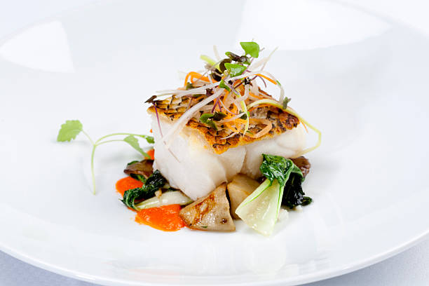 Dinner Grilled Sea Bass dinner, with vegetables on white plate. white restaurant dishes stock pictures, royalty-free photos & images