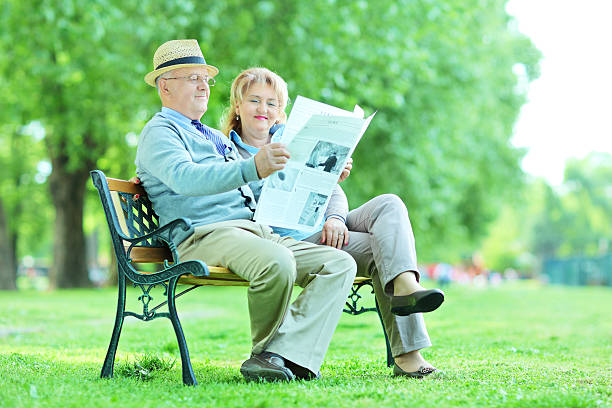 istock Mature couple reading a newspaper in park 497303609