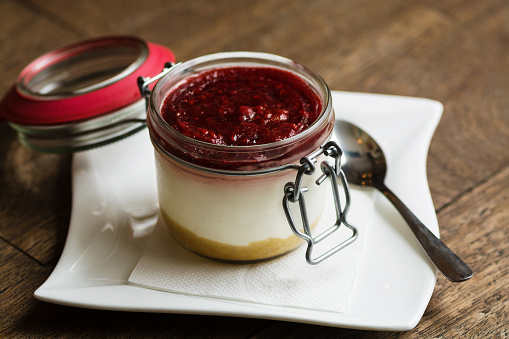American style cheese cake served in a jar on a wooden table