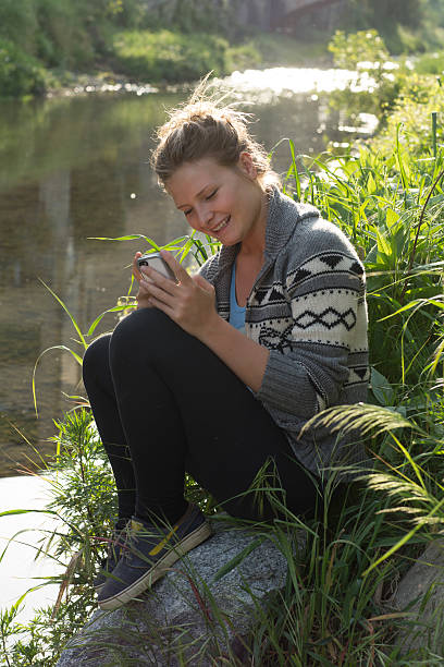 istock Young woman smiling at smart phone text message 497311813