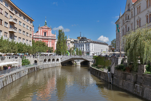 Ljubljana, Slovenia - September 6, 2015:People walk along Ljubljanica River with Franciscan Church and Triple Bridge.