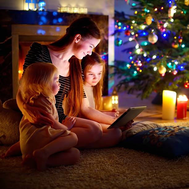 istock Mother and daughters using tablet by a fireplace on Christmas 497315400