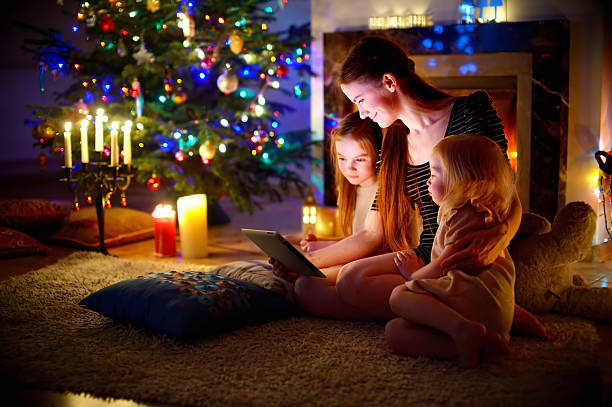 istock Mother and daughters using tablet by a fireplace on Christmas 497315568