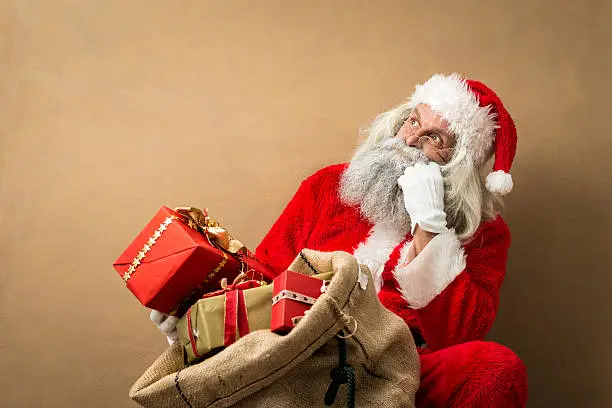 Photo of santa claus with many gifts in his bag