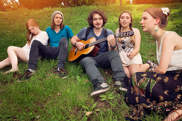 istock Group of young people singing and playing guitar in park. 497341107