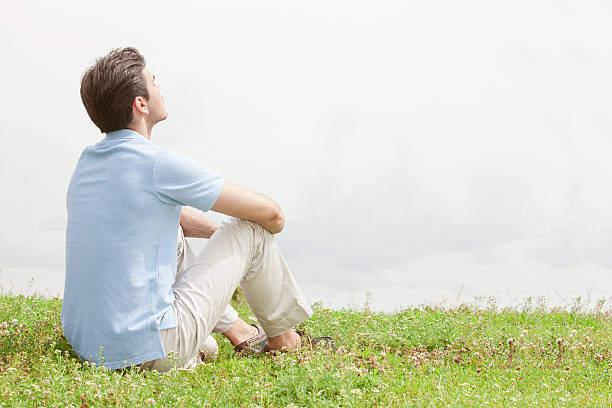 istock Rear view of relaxed young man sitting on grass 497341653