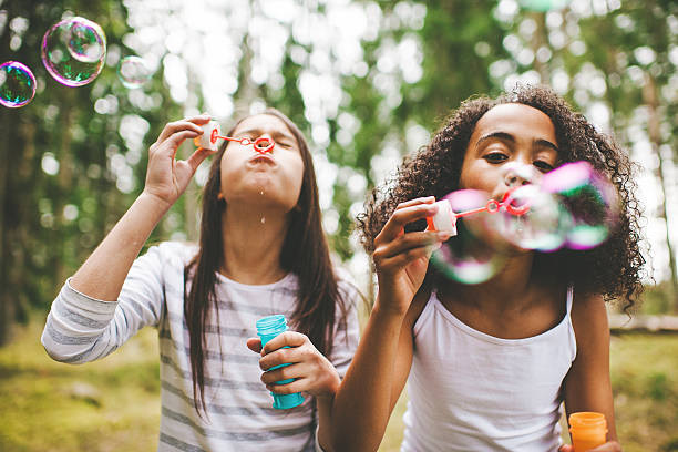 linda niñas soplando burbujas de aire libre - bubble wand bubble child playful fotografías e imágenes de stock