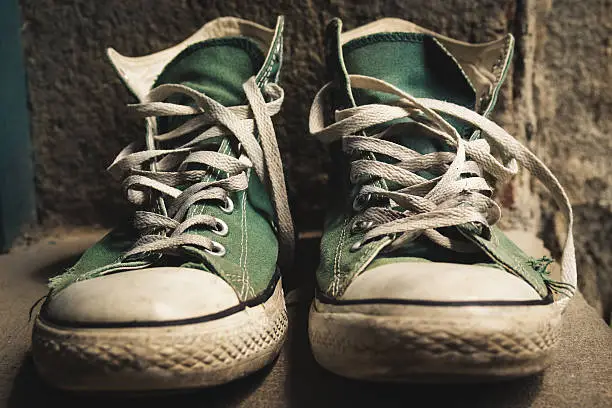 Old green converse shoes and worn laces