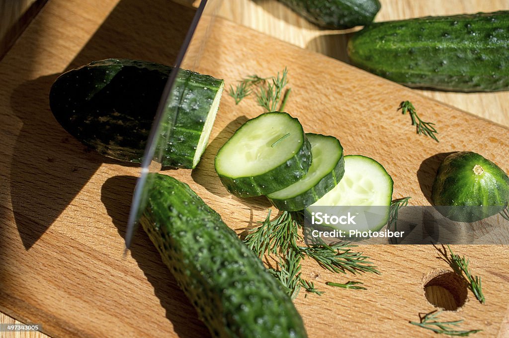 Cucumbers Cucumbers cut knife on a wooden board and dill. Backgrounds Stock Photo