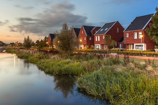 Long exposure night shot of a Street with modern ecological middle class family houses with eco friendly river bank in Veenendaal city, Netherlands.