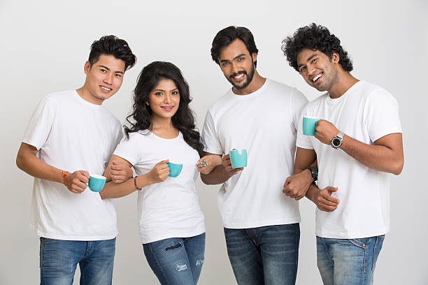 Happy small group of young people posing with coffee cup on grey background.