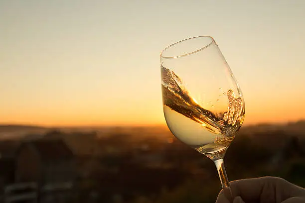 White wine in crystal glass against sunset.