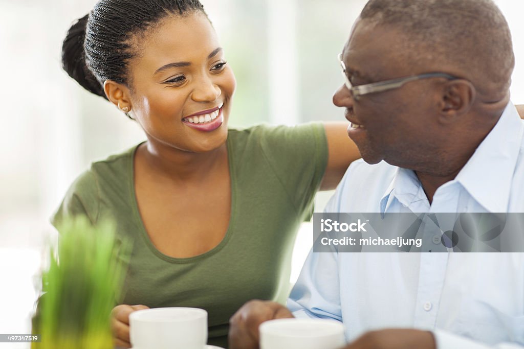elderly african american man enjoying coffee with his granddaughter smiling elderly african american man enjoying coffee with his granddaughteer at home Father Stock Photo