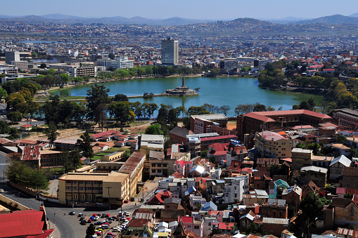 Antananarivo, Madagascar: skyline - view from the Haute Ville - Anosy Lake with its War Memorial at the end of a causeway - panoramic view of downtown - photo by M.Torres
