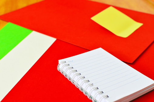 Open notebook and yellow post it isolated on red background