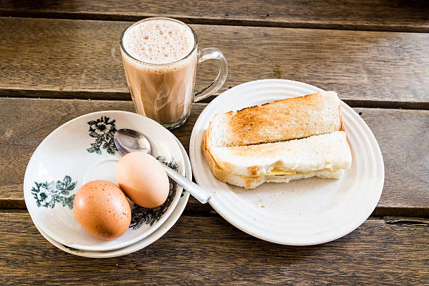 Popular Malaysian breakfast teh tarik, toast bread and half-boil Common oriental breakfast set in Malaysia consisting of teh tarik, toast bread and half-boiled egg kopitiam egg stock pictures, royalty-free photos & images