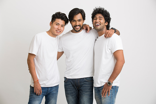 Smart Indian young male friends laughing on white background.