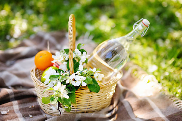 Picnic basket with fruits, flowers and water in the glass bottle