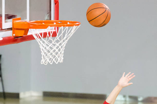 Close up of basket ball in basket with arm and hand of player