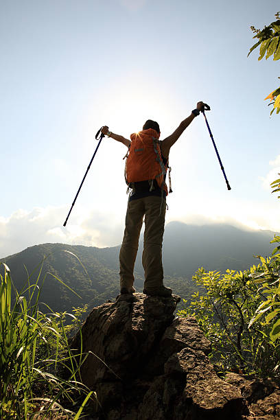 istock cheering woman hiker open arms at mountain peak cliff 497354370