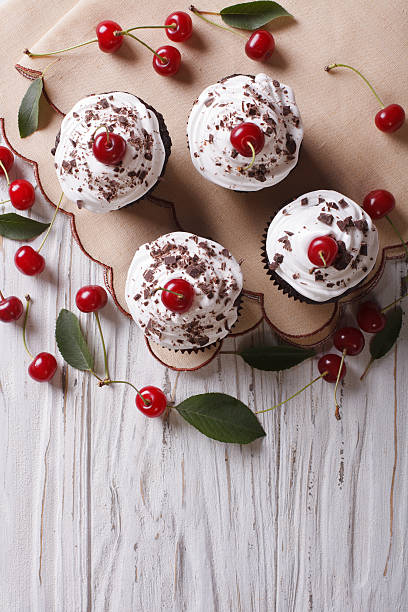 istock Chocolate cupcakes with cream and cherry vertical top view 497355748