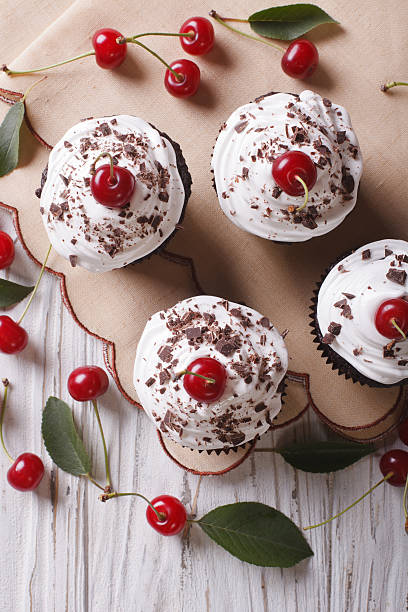 istock Chocolate cupcakes with cream and cherry closeup vertical top view 497355932