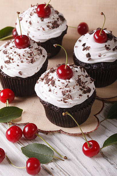 istock Beautiful chocolate cupcakes with white cream and cherry, vertical 497356104