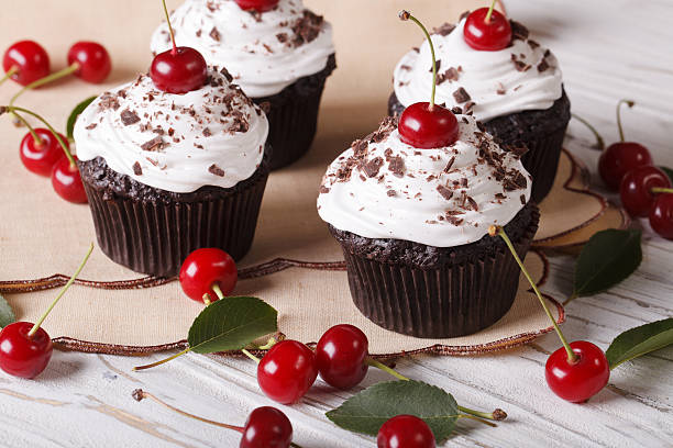 istock Beautiful chocolate cupcakes with white cream and cherry, horizo 497356236