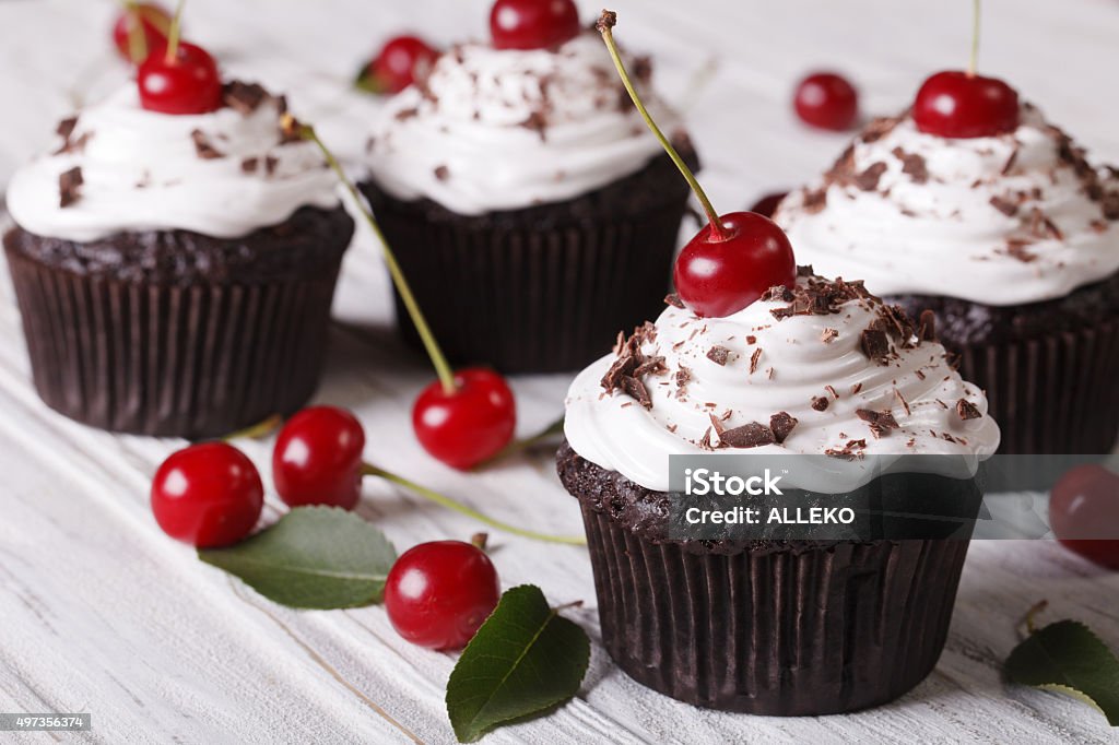 Chocolate cupcakes with cream and fresh cherry horizontal Chocolate cupcakes with cream and fresh cherry Black Forest close up on the table. horizontal Cream - Dairy Product Stock Photo