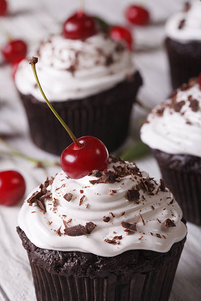 istock Chocolate cupcakes with cream and cherry close up, Vertical 497357048