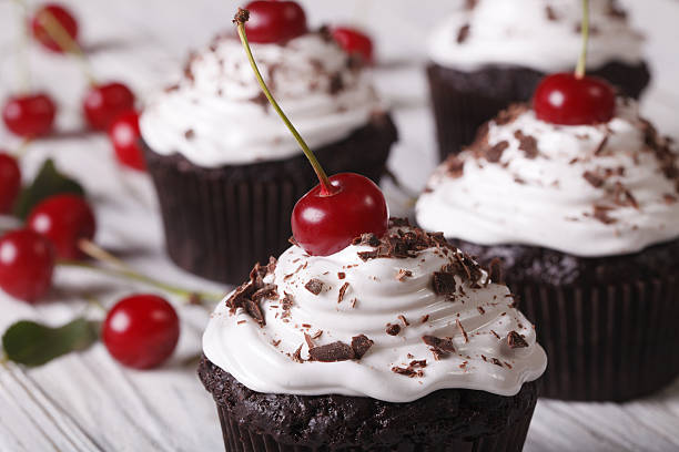 istock Chocolate cupcakes with white cream and cherry, horizontal macro 497357186