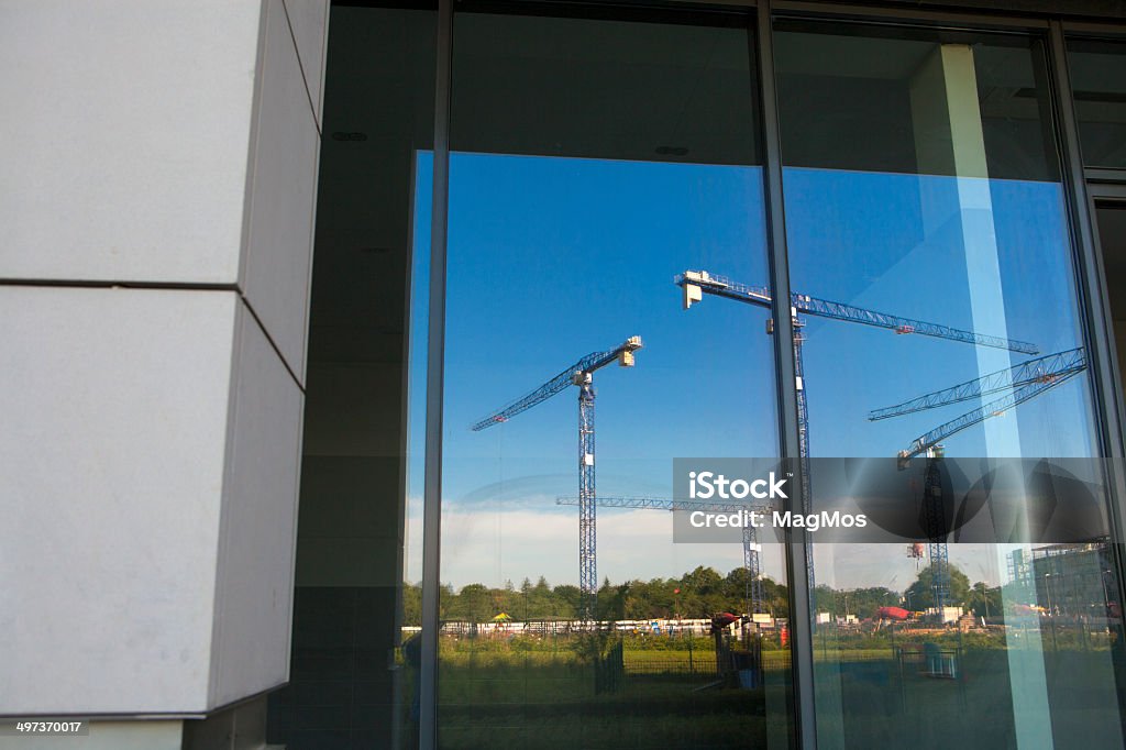 Construction cranes reflected in  window Architecture Stock Photo