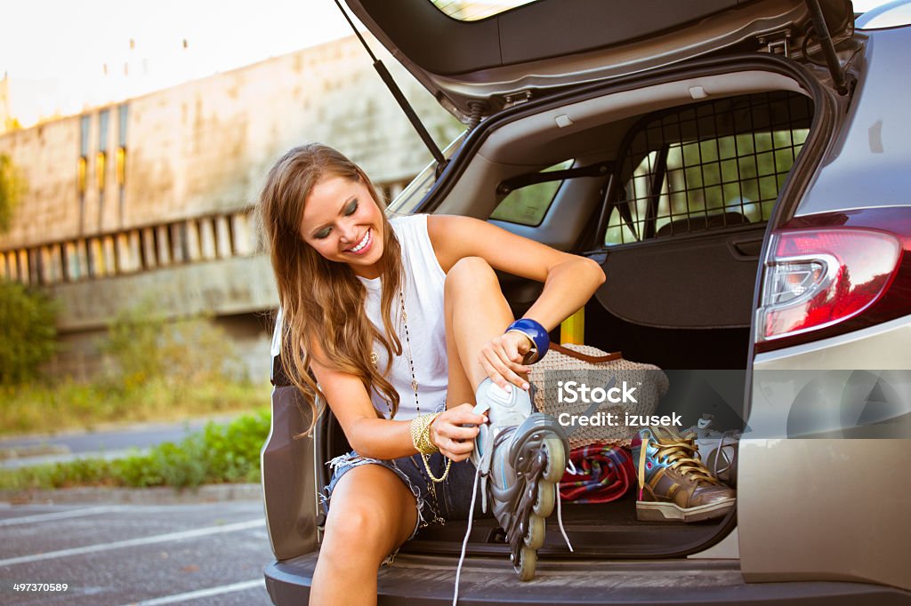 Young female skater Young female skater sitting in a back of van and ties her rollers. Car Stock Photo