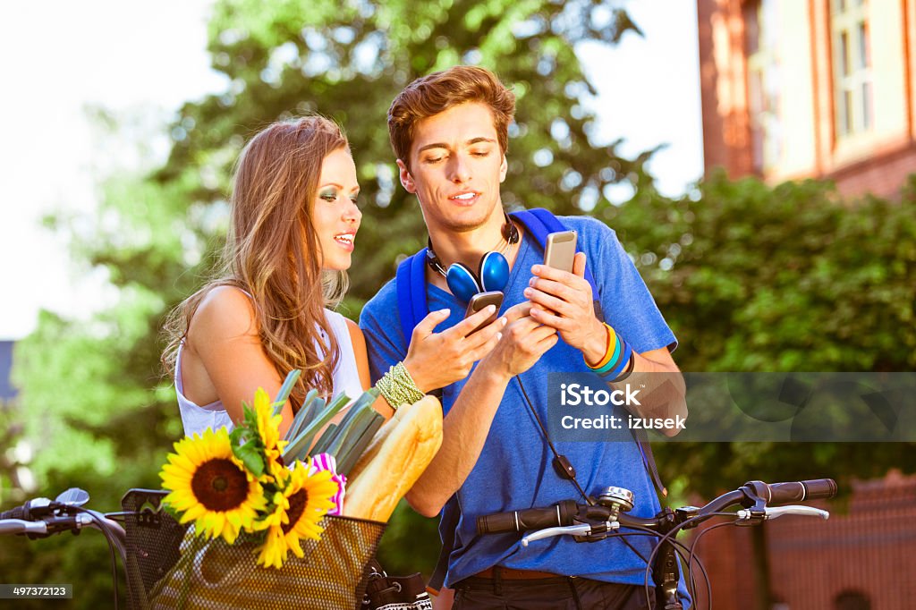 Urban young people using smart phones Outdoor portrait of young couple using their smart phones. Flirting Stock Photo