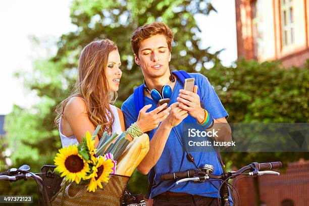 Urban Young People Using Smart Phones Stock Photo - Download Image Now - Flirting, Bicycle, Couple - Relationship