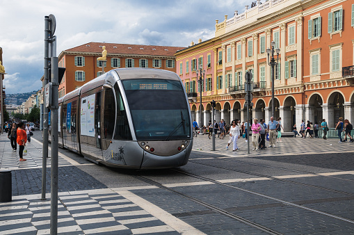 Nice, France- June 4, 2014: Shoppers wait to cross   Place Massena until the Tramway Lignes D'Azur clears the open plaza.  Carrying 90,000 passengers daily, the modern tramway dramaticly cuts vehicular traffic in the city.