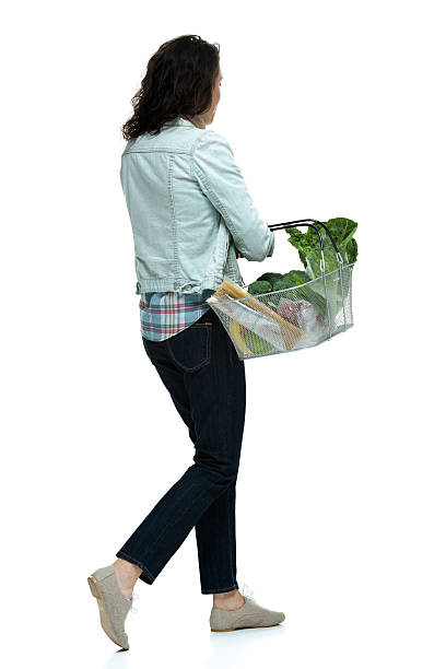 istock Woman walking & holding vegetable basket 497372883