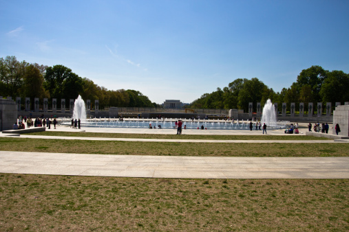 Washington DC, USA - May 3, 2013: Washington monument panorama and WWII memorial with fountains and light during the day, Washington DC. Located between the Lincoln Memorial and Washington Monument, the World War II Memorial is dedicated to all who fought in the Second World War. It is not only a landmark and sightseeing for tourists, but also the site where American veterans are brought to be honored for their services and sacrifices.