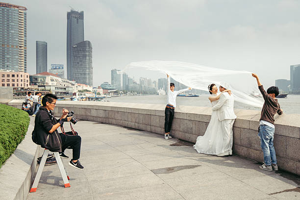 Shanghai, China - October 26, 2015: Photo session on the Bund in Shanghai. A couple of Chinese modeling for wedding picture on Bund's sidewalk. The modern skyline of Lujiazui and Pudong can be seen in the background.