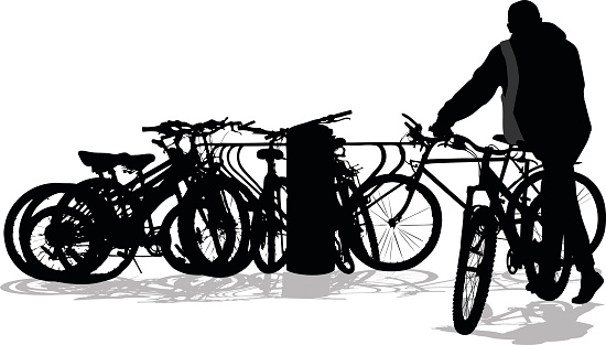 A vector silhouette illustration of a young man dismounting his bike to park it at a crowded bike rack.