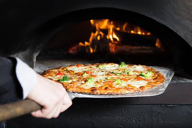 pizza abbandonando al peel da slove calda - pizzeria foto e immagini stock