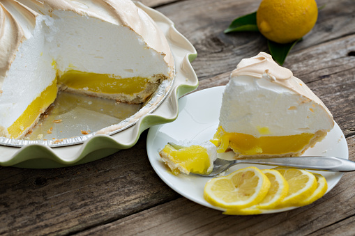 A high angle extreme close up shot of a lemon meringue pie and some lemon slices.